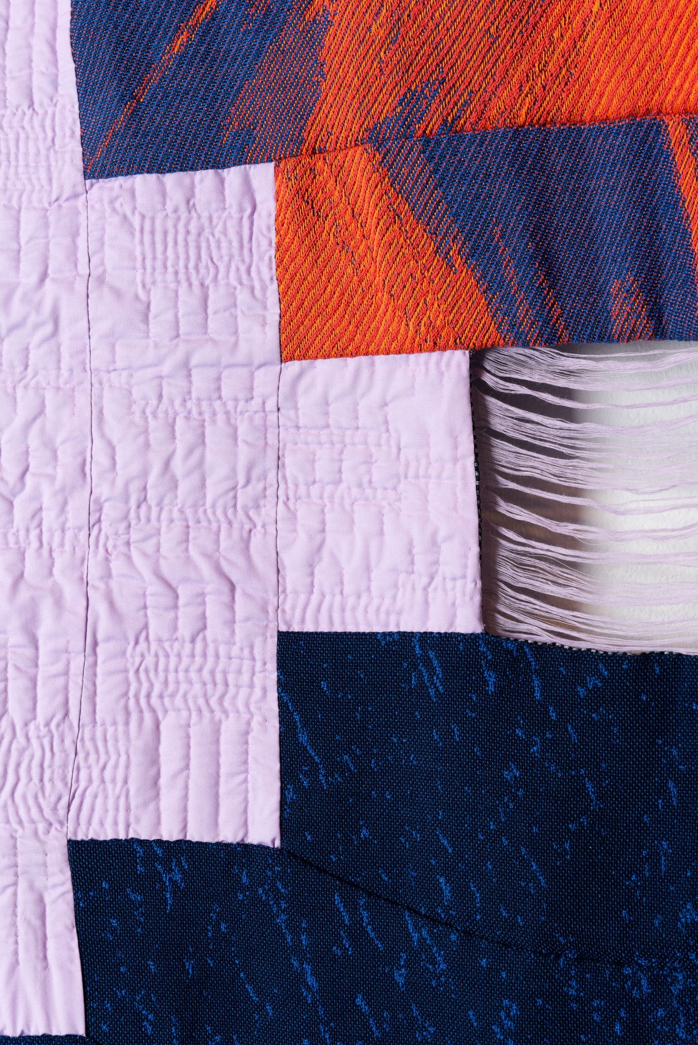 Close-up photograph of a woven patchwork in pink, red, blue and black